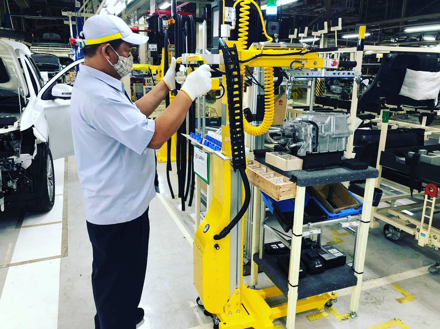 An operator using the yellow FPDU assist device in real production on the PHEV line