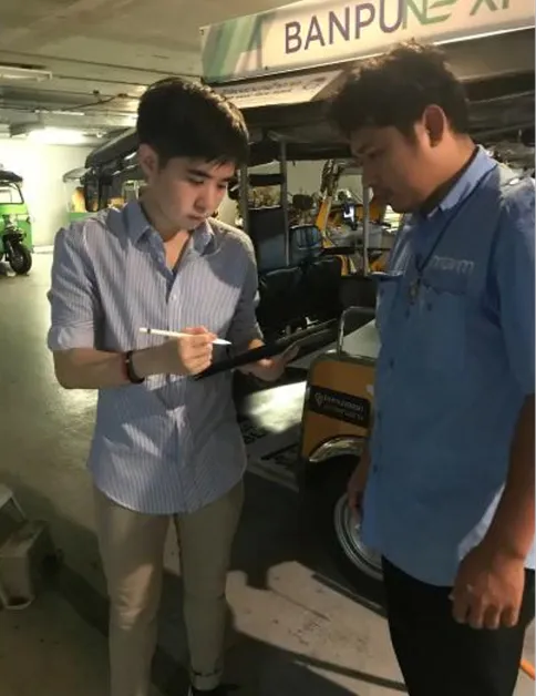 Chatree gathering requirements from a MUVMI driver beside an electric tuk-tuk